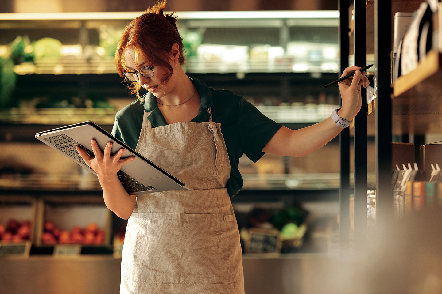 A retail worker using a 2-in-1 laptop in tablet mode in a grocery store aisle.