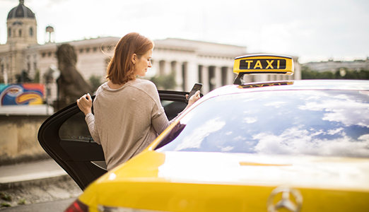 A person looking at their smartphone while entering a taxi.